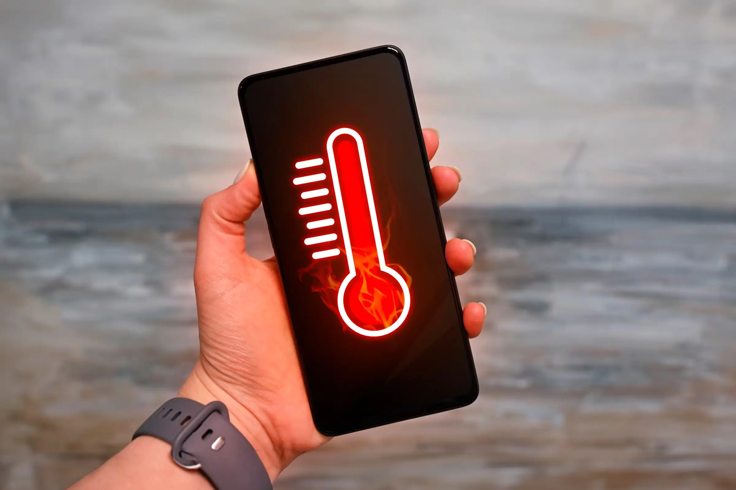 a-hand-holding-a-smartphone-with-a-thermometer-indicating-that-the-device-is-overheating داغ شدن موبایل